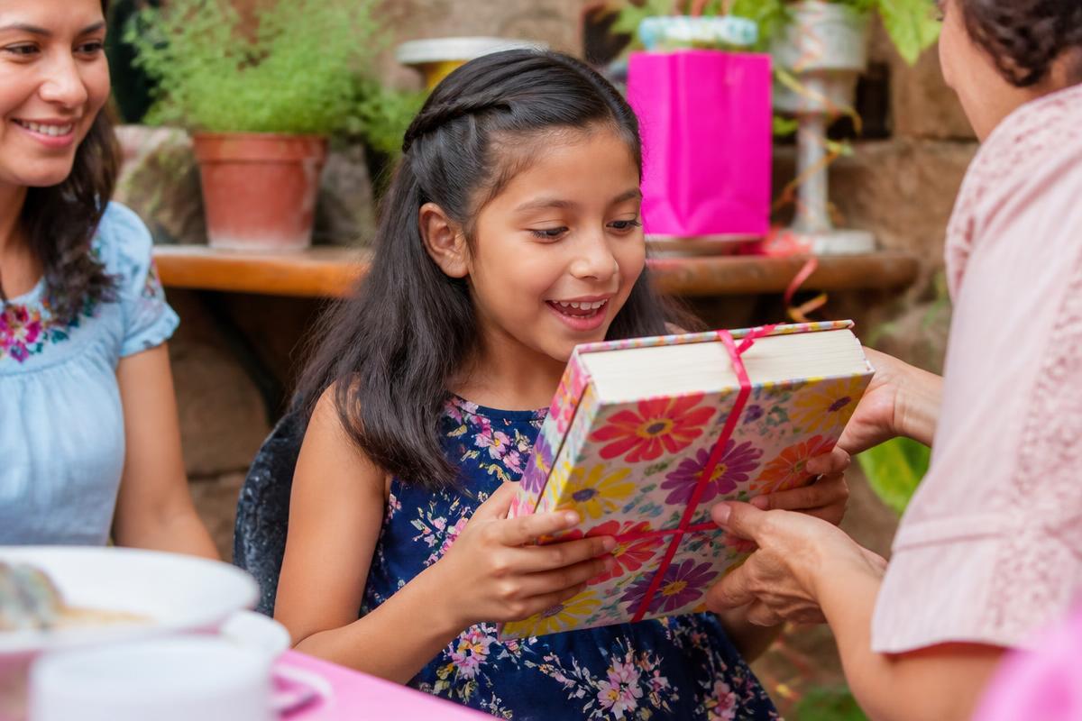 Chica recibiendo un libro de regalo en su cumpleaños